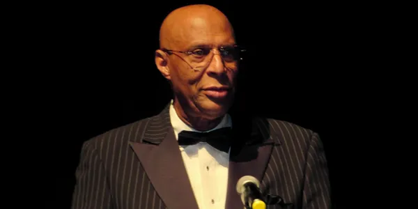 Man in tuxedo speaking at microphone